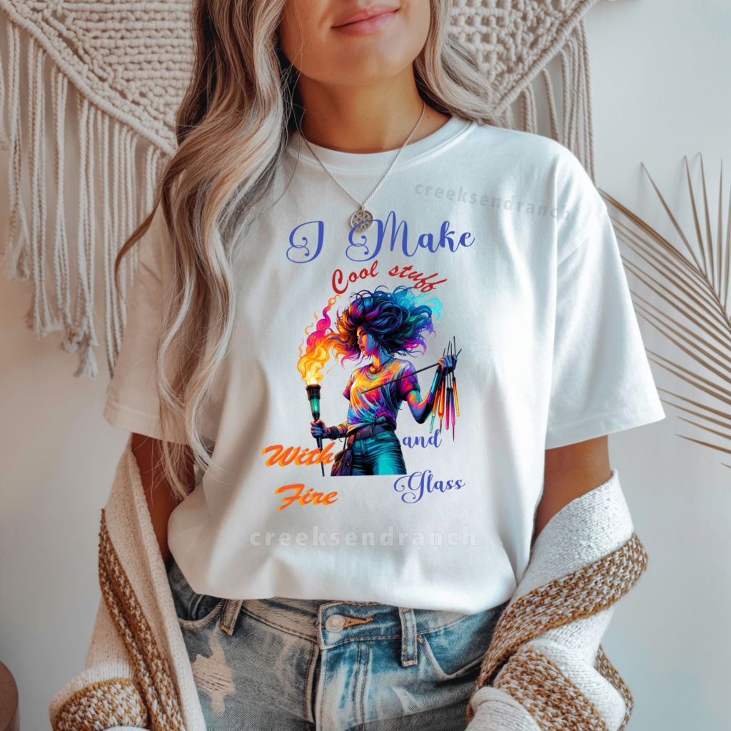 Torso shot of a person in a white graphic T-shirt with a colorful illustration, wearing a beige knit cardigan and blue jeans.