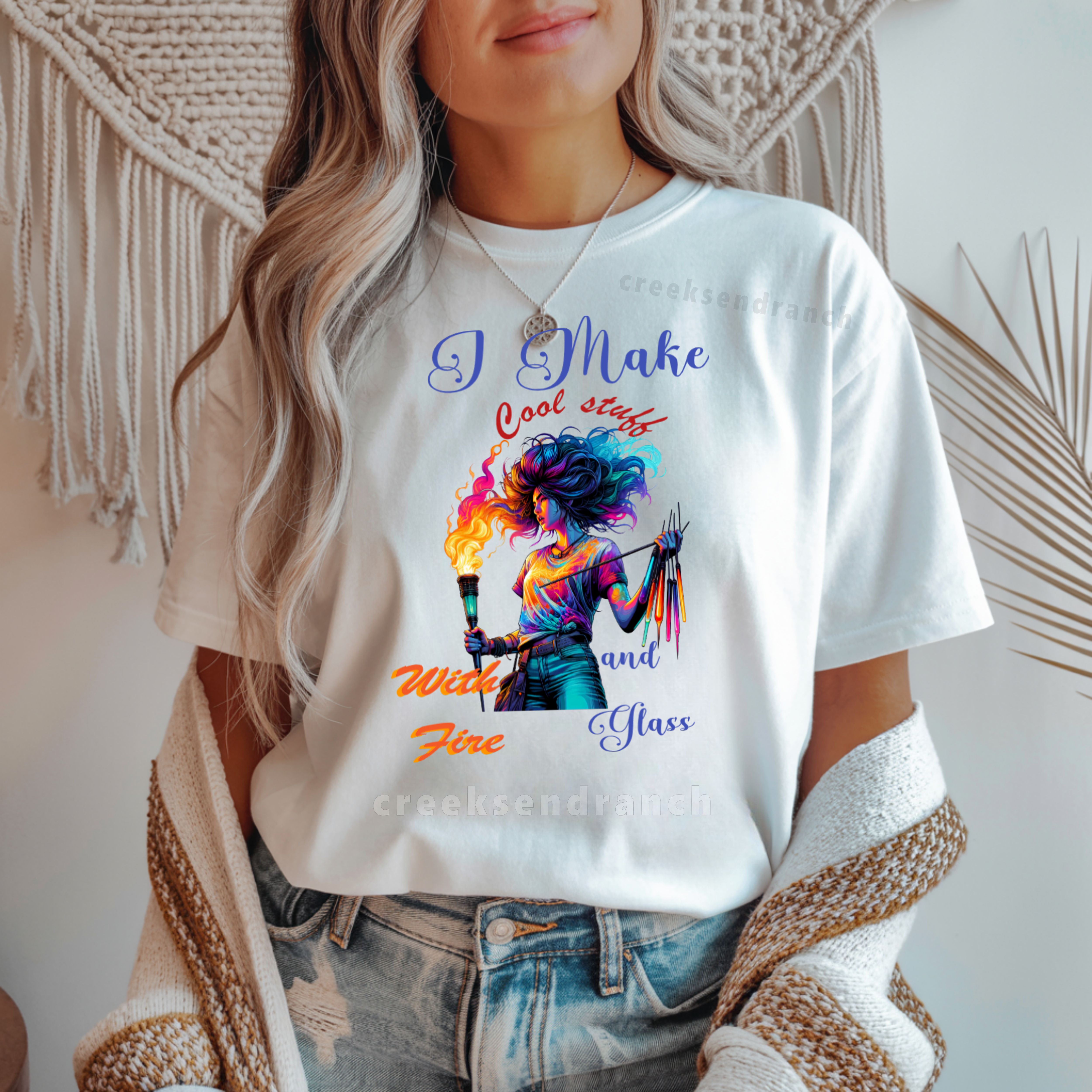Torso shot of a person in a white graphic T-shirt with a colorful illustration, wearing a beige knit cardigan and blue jeans.